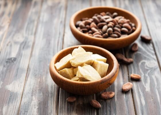 Natural cocoa butter and cocoa beans on a old wooden background
